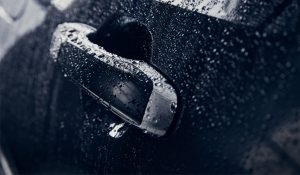 Nærbilde av svart bildør som er dekket med vanndråper