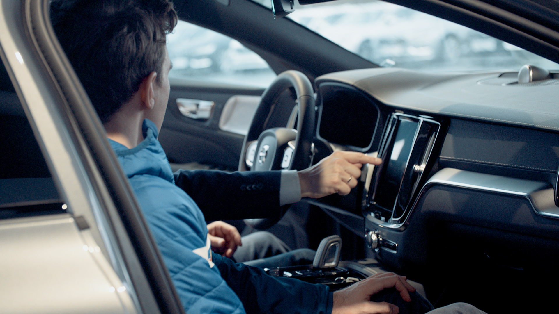 To personer sitter i fremsetene av en bil og ser på digital sjarm