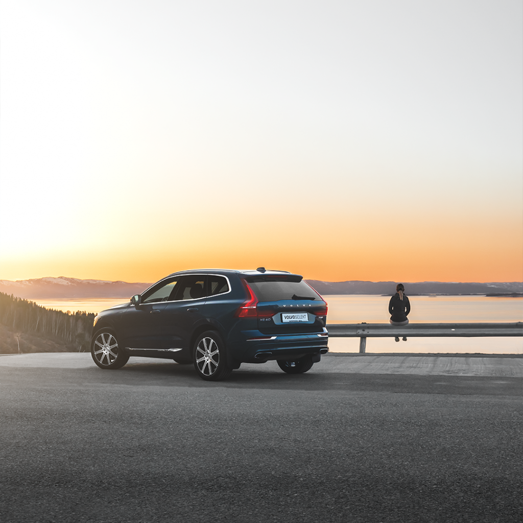 Mørk blå Suv fra Volvo parkert på et utsiktspunkt med solnedgang i bakgrunnen