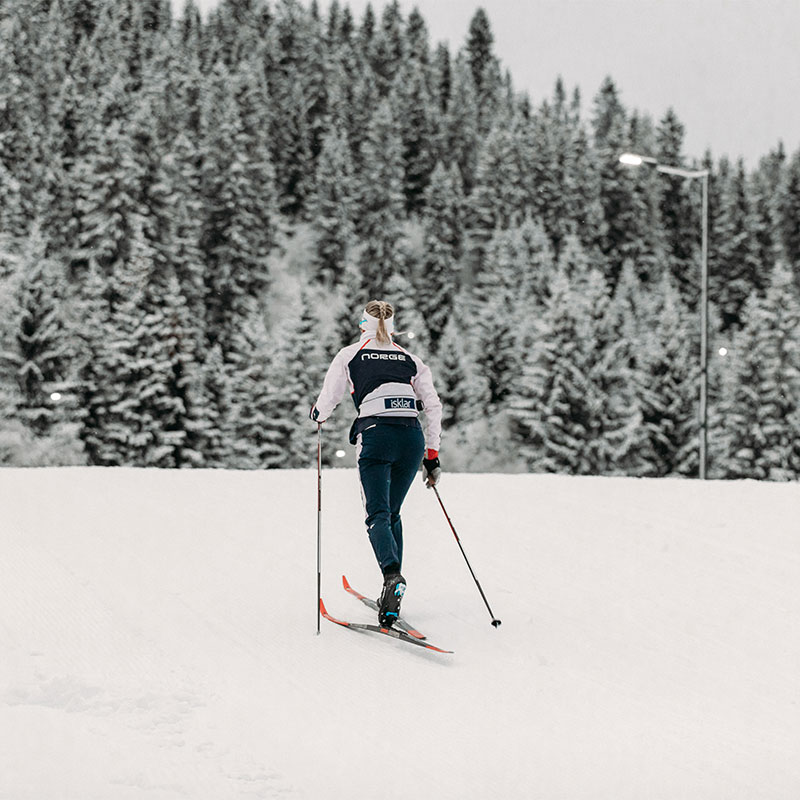 Kvinne går på ski med snøkledde trær i bakgrunnen