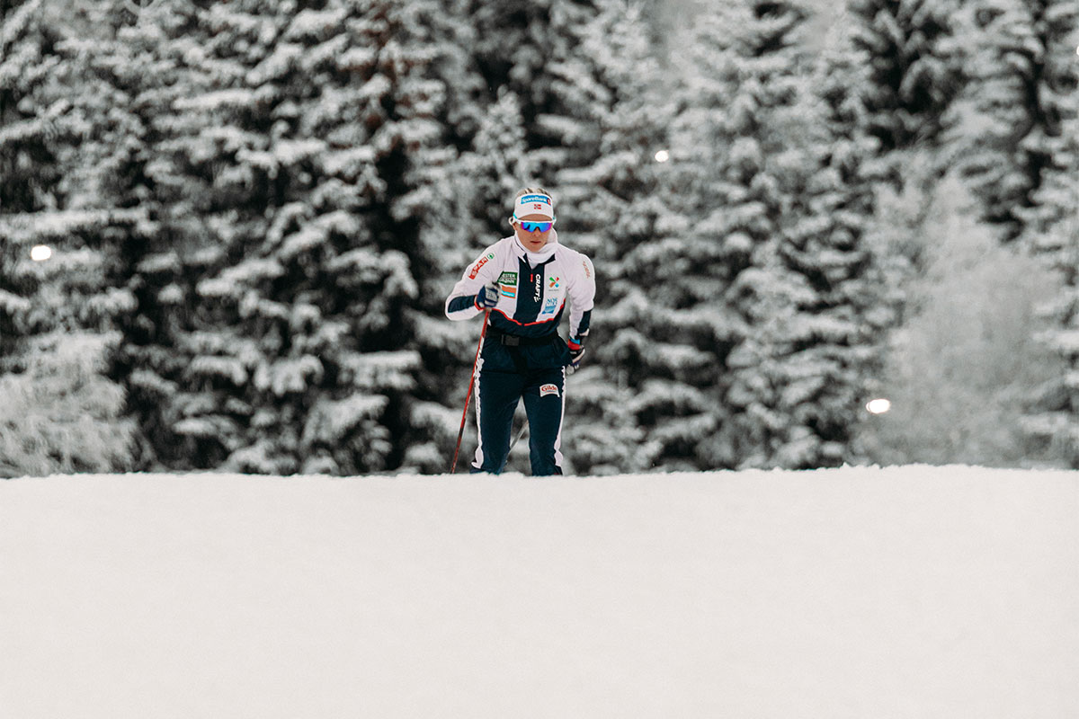 Kvinne går på ski med snøkledde trær i bakgrunnen