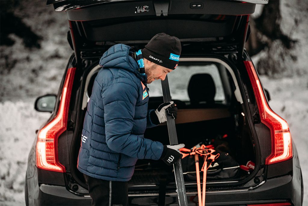 Mann /Emil Iversen) smører ski bak bil med bagasjerommet åpent