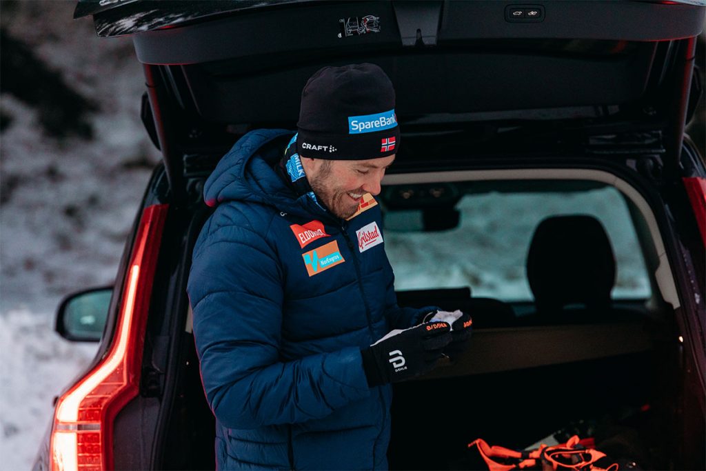 Emil Iversen i blå boblejakke foran et åpent bagasjerom på en Volvo