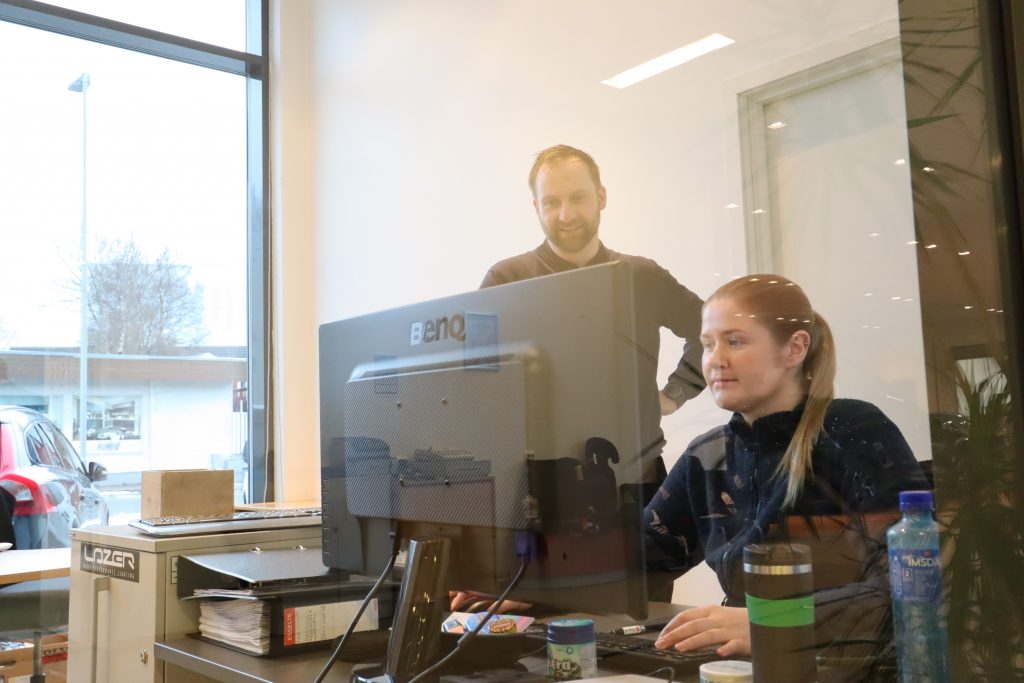 En mann og en dame ser på en dataskjerm på et kontor