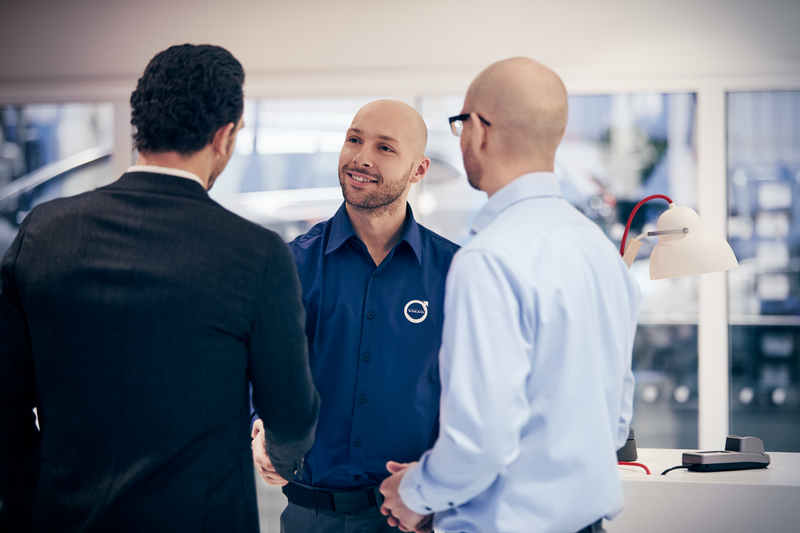 Tre menn snakker sammen hos en Volvo-forhandler
