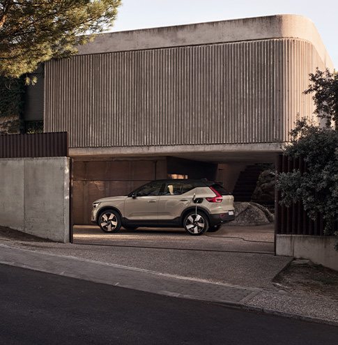 En sandfarget Volvo EX40 sett fra siden i en betonggarasje