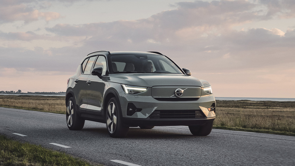Grønn Suv fra Volvo kjørende på vei langs gresslette