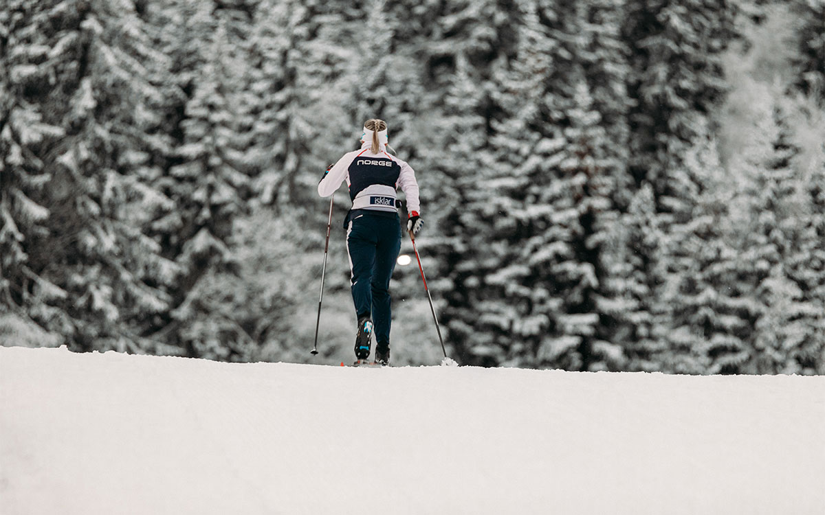 Kvinne går på ski med snøkledde trær i bakgrunnen